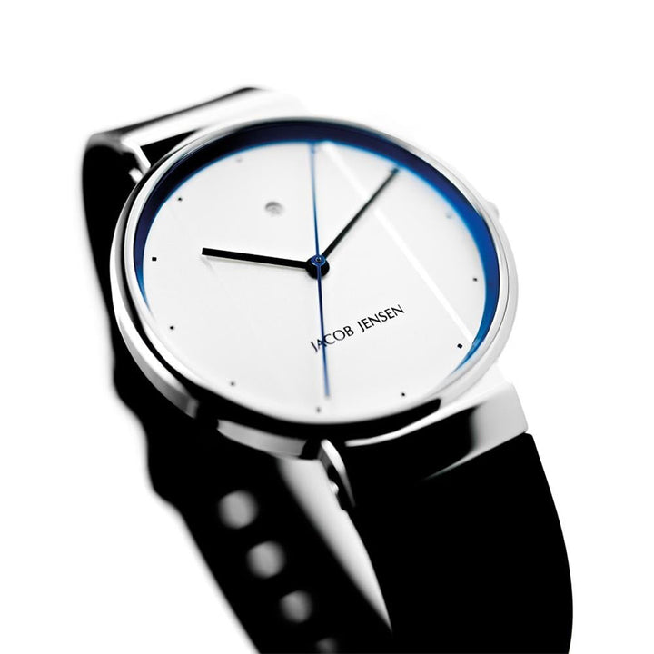 De Jacob Jensen 750 is een strak, modern quartzhorloge met een minimalistisch ontwerp met een witte wijzerplaat, dunne zwarte wijzers, kleine zwarte uurstippen en een glanzende roestvrijstalen lunette in combinatie met een klassieke zwarte band.