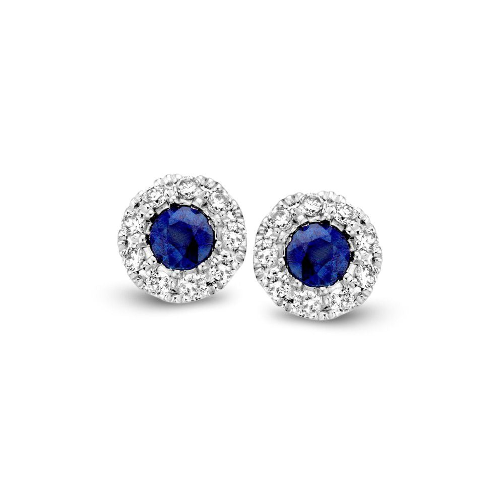 De Bicolor Gouden Oorknoppen met Saffier en Diamanten 0,11ct van Excellent Jewelry hebben ronde ontwerpen met diepblauwe saffieren en fonkelende diamanten in het midden, elk omringd door een halo van kleine heldere stenen gezet in zilver.