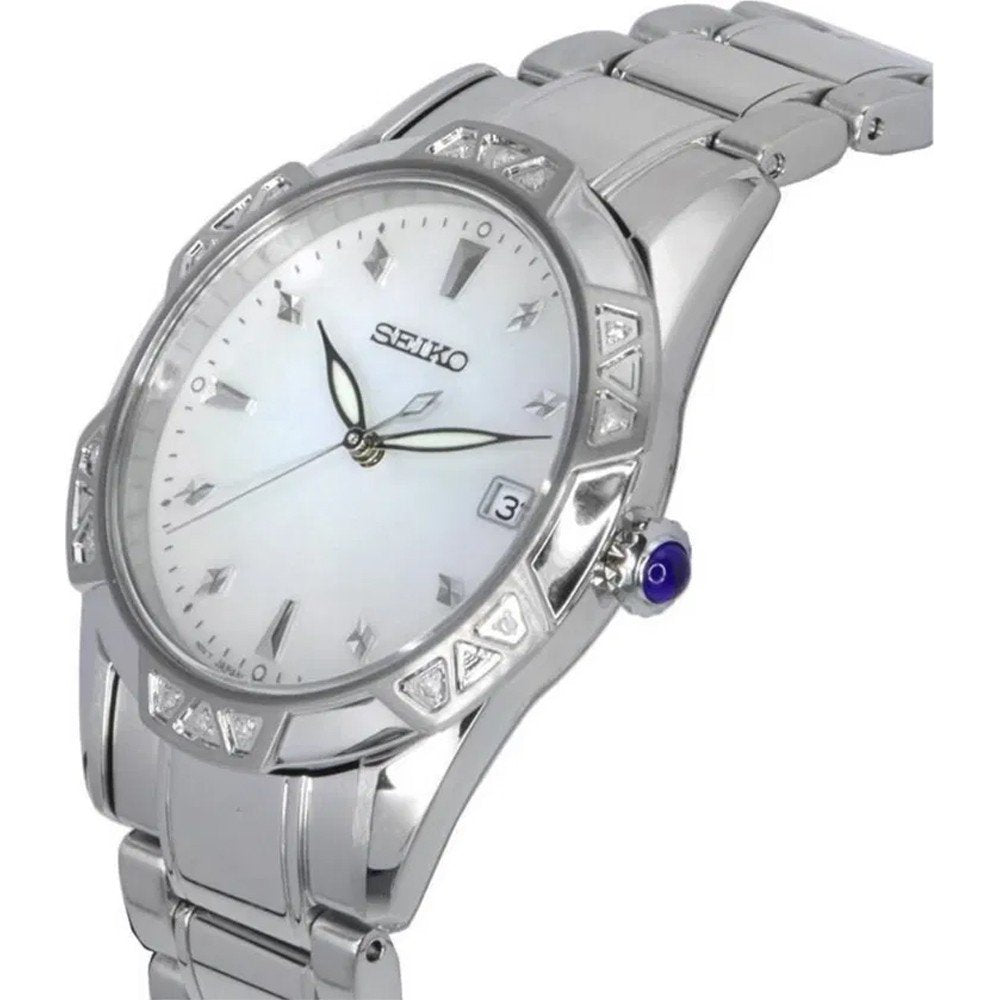 Het Seiko dameshorloge SKK727P1 heeft een roestvrijstalen band, witte wijzerplaat, Quartz-uurwerk, Romeinse cijfers als uurmarkeringen, lichtgevende wijzers, datumvenster op 3 uur, driehoekige lunette-accenten, een blauwe kroon en is waterbestendig tot 10 ATM.