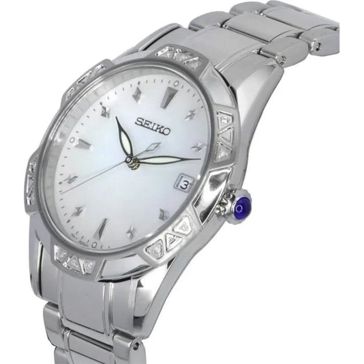 Het Seiko dameshorloge SKK727P1 heeft een roestvrijstalen band, witte wijzerplaat, Quartz-uurwerk, Romeinse cijfers als uurmarkeringen, lichtgevende wijzers, datumvenster op 3 uur, driehoekige lunette-accenten, een blauwe kroon en is waterbestendig tot 10 ATM.