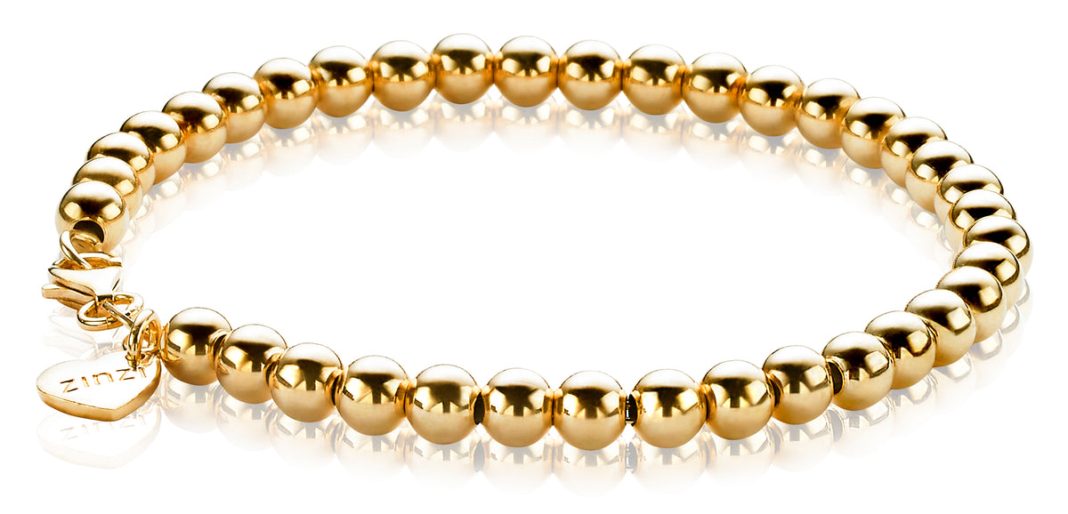 Goldplattiertes Armband mit runden, glänzenden Perlen und einem kleinen Anhänger