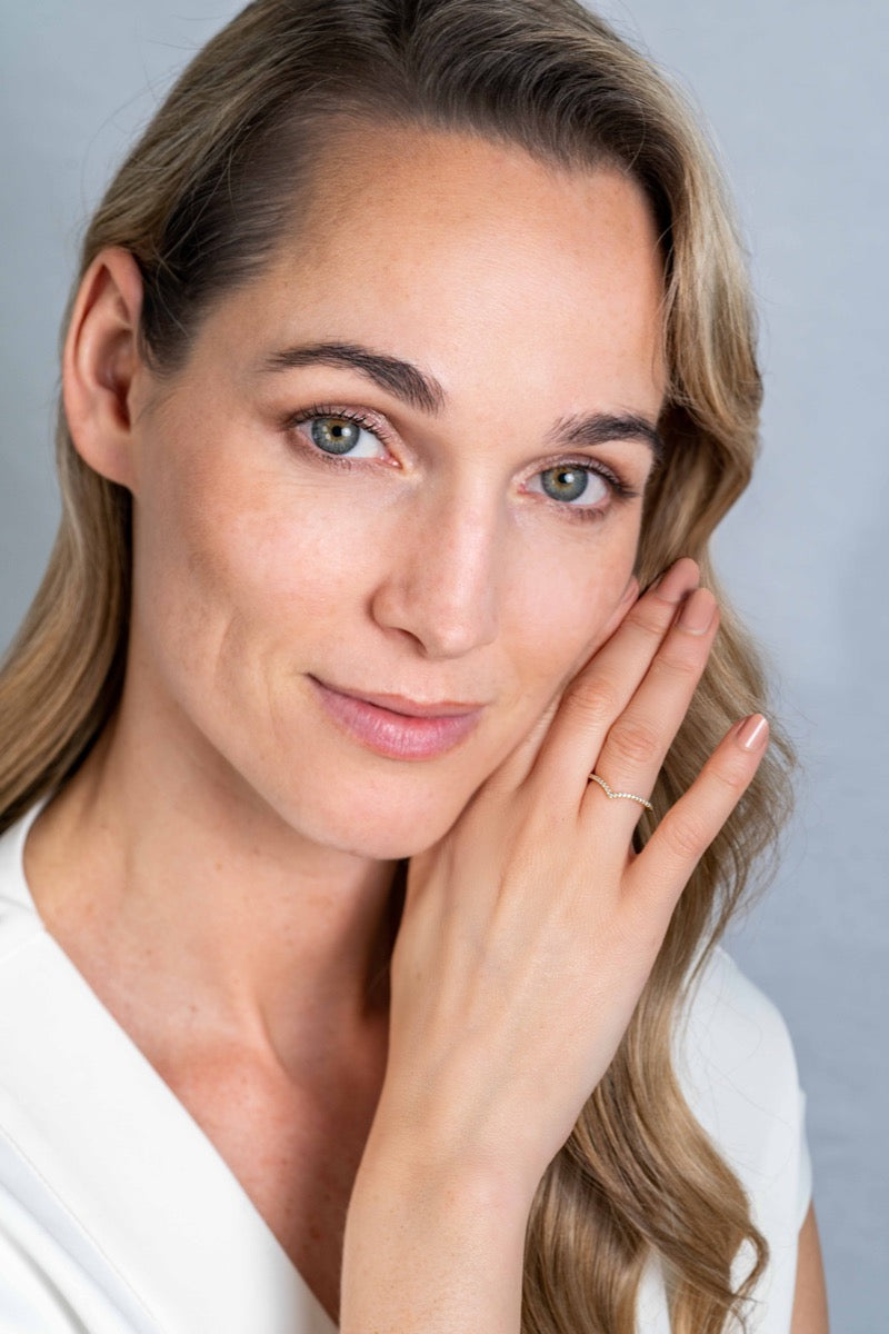 Goldener Ring mit feinem Design, auf einem Finger einer Frau getragen
